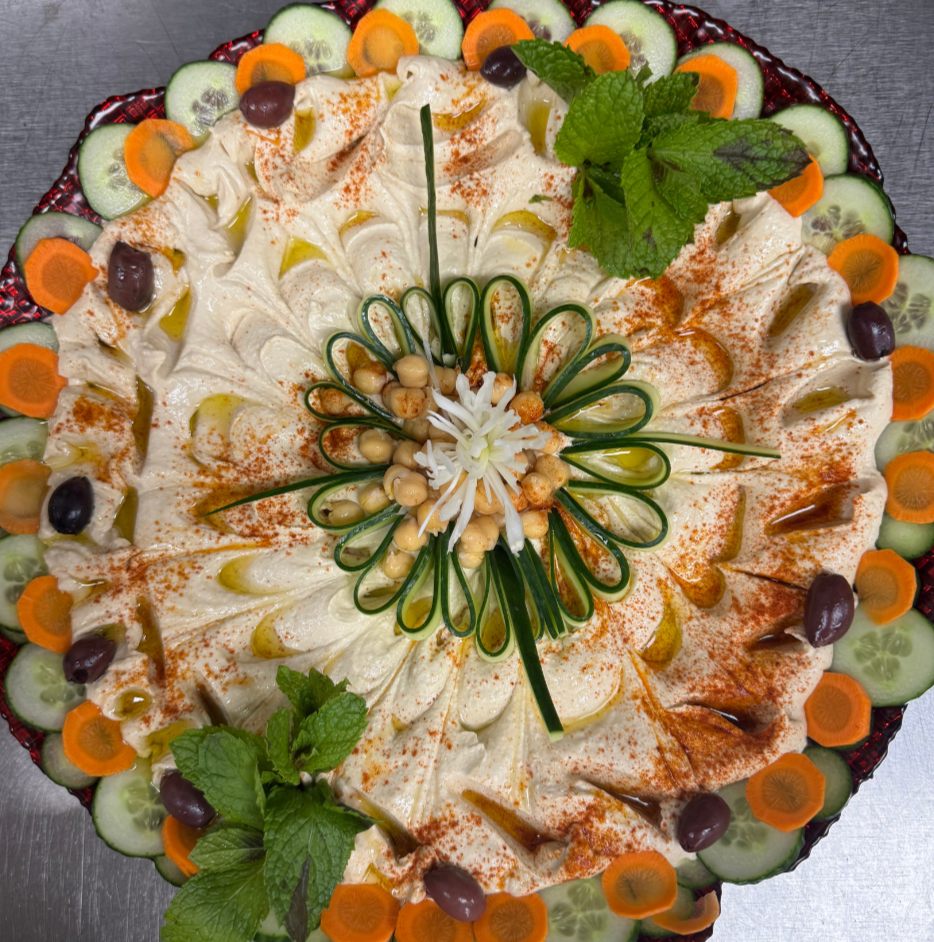 Hummus tray garnished with cucumber, carrot and olives